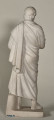 Aischines. Posąg marmurowy przedstawia mężczyznę w średnim wieku okrytego himationem, stojącego ze zgiętą i odsuniętą w bok prawą nogą, z rękoma schowanymi pod szatą, prawa spoczywa na piersiach, lewa z tyłu poniżej pasa. Tył