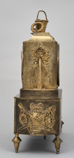 Bok zegara kominkowego w kolorze złotym z dekoracjami  rzeźbiarskimi