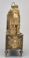 Bok zegara kominkowego w kolorze złotym z dekoracjami rzeźbiarskimi