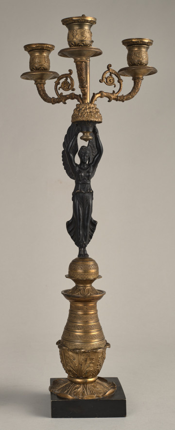Kandelabr trzyświecowy z postacią uskrzydlonej Nike na postumencie, trzymającej ramiona świecznika.