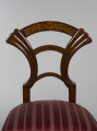 zbliżenie na opracie w kształcie wachlarza ze zdobieniem (ntarsjowane gałązki tworzące symetryczne arabeski złączone pośrodku stylizowanym motywem liry) oraz na tapicerowane siedzisko krzesła obite malinowym jedwabiem w paski