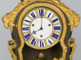 zbliżenie na dekorację na szczycie obudowy zegara -  dwie koźle głowy symbolizujące witalność oraz tarczę zegara