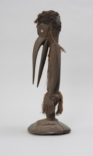 rzeźba przodka przedstawiająca dzioborożca - Ujęcie boku z lewej; Drewniana, antropomorficzna rzeźba z nosem przypominającym ptasi dziób.