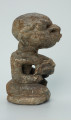 rzeźba; przedmiot obrzędowy; Figura kultu sił wegetacji - Ujęcie prawy bok. Rzeźbiona w białoszarym steatycie siedząca na płaskiej, owalnej podstawie kobieta trzymająca w dłoniach, przy biuście zwrócone ku niej dziecko.