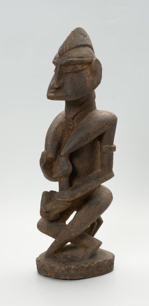 drewniana, rzeźbiona figura - Ujęcie z przodu, z lewej strony. Drewniana, rzeźbiona postać kobiety, trzymającej w ramionach małe dziecko.