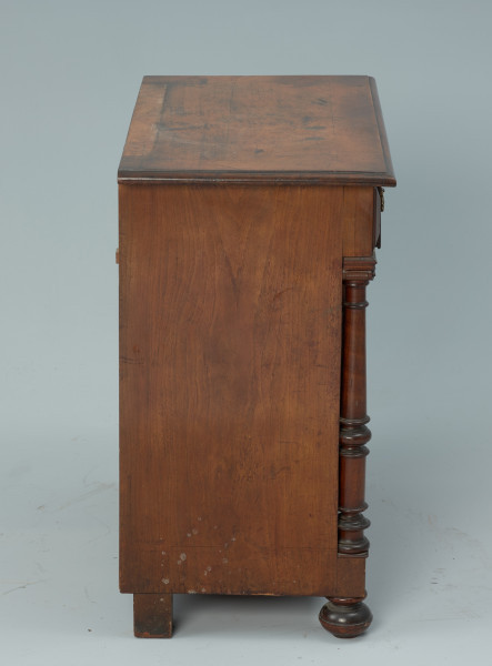 szafka - Ujęcie z lewego boku. Szafka w typie bieliźniarki z drewna fornirowanego, przeznaczona pod lustro, dwudrzwiowa z szufladą górną.