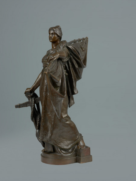 posąg - Ujęcie z prawej strony; Stojąca młoda kobieta w powłóczystej szacie, z żaglem na lewym ramieniu, z prawą ręką opartą o kotwicę. Rzeźba jest pomniejszoną kopią figury wieńczącej fontannę postawioną w 1895 r. na obecnym placu tobruckim.