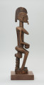 drewniana figura - Ujęcie z prawego boku. Drewniana, rzeźbiona figura kobiety, siedzącej na stołku.