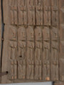 drewniane drzwiczki do spichlerza - Ujęcie z przodu, zbliżenie na środek. Dwuczęściowe połączone żelaznymi klamrami drewniane drzwiczki do spichlerza. Całość udekorowana płaskorzeźbionymi postaciami. W środku lewego brzegu zamek.