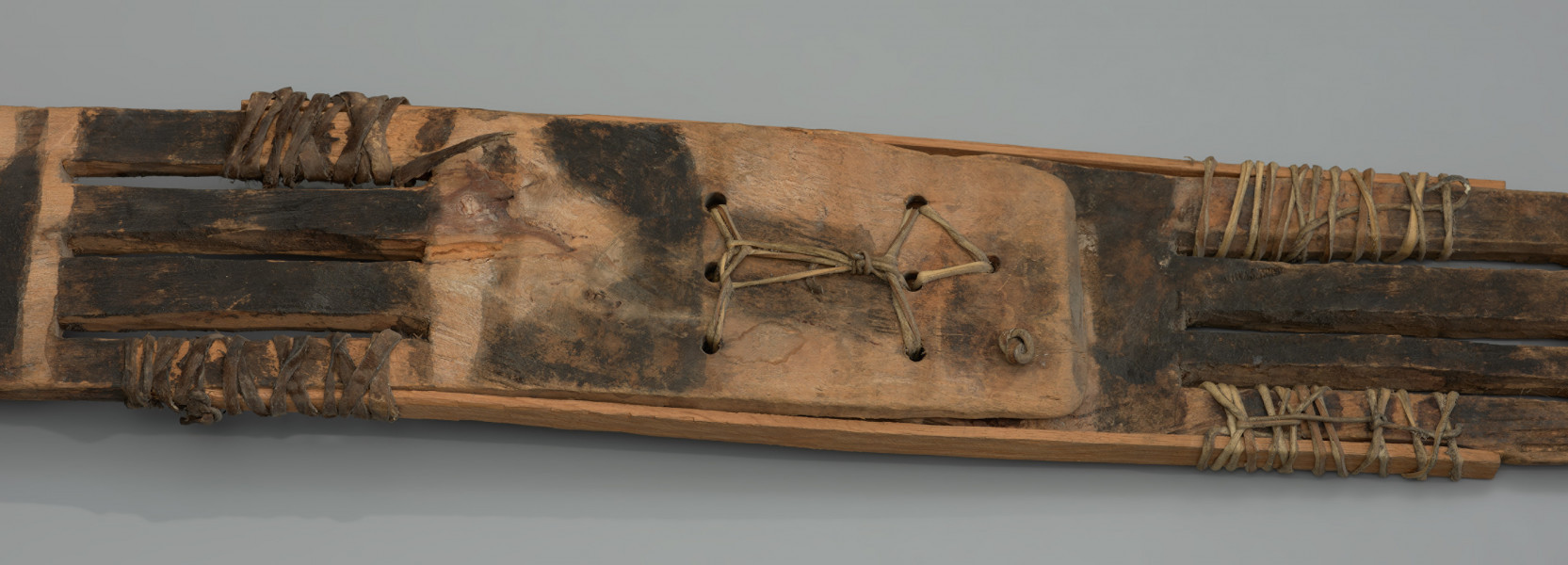 maska sirige - Ujęcie drugiego detalu. Drewniana, rzeźbiona maska w kształcie długiej deski.
