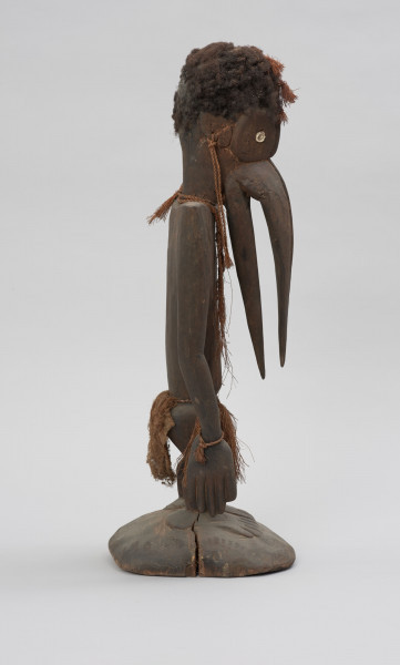 rzeźba przodka przedstawiająca dzioborożca - Ujęcie z boku z prawej; Drewniana, antropomorficzna rzeźba z nosem przypominającym ptasi dziób.