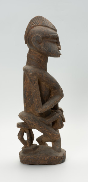 drewniana, rzeźbiona figura - Ujęcie z prawego boku. Drewniana, rzeźbiona postać kobiety, trzymającej w ramionach małe dziecko.