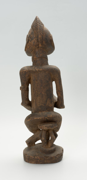 drewniana, rzeźbiona figura - Ujęcie z tyłu. Drewniana, rzeźbiona postać kobiety, trzymającej w ramionach małe dziecko.