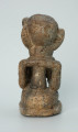 rzeźba; przedmiot obrzędowy; Figura kultu sił wegetacji - Ujęcie z tyłu. Rzeźbiona w białoszarym steatycie siedząca na płaskiej, owalnej podstawie kobieta trzymająca w dłoniach, przy biuście zwrócone ku niej dziecko.
