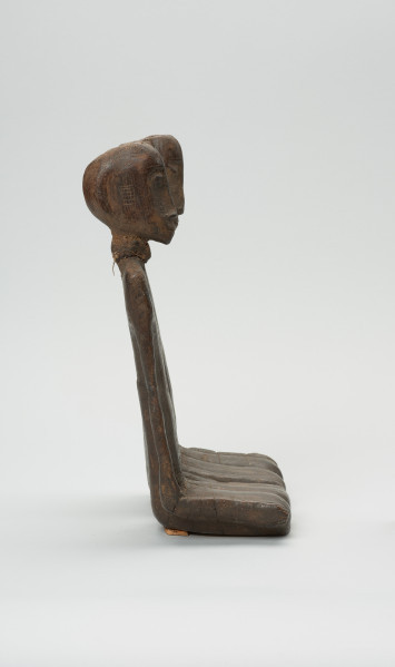 drewniana figura - Ujęcie z lewego boku. Para przodków siedzących obok siebie, ręce przylegające wzdłuż tułowia.