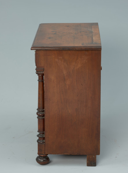 szafka - Ujęcie z prawego boku. Szafka w typie bieliźniarki z drewna fornirowanego, przeznaczona pod lustro, dwudrzwiowa z szufladą górną.