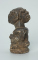 rzeźba; przedmiot obrzędowy; Figura kultu sił wegetacji - Ujęcie lewy bok. Rzeźbiona w grafitowym steatycie siedząca postać ludzka o dwóch twarzach, z przodu i z tyłu głowy.