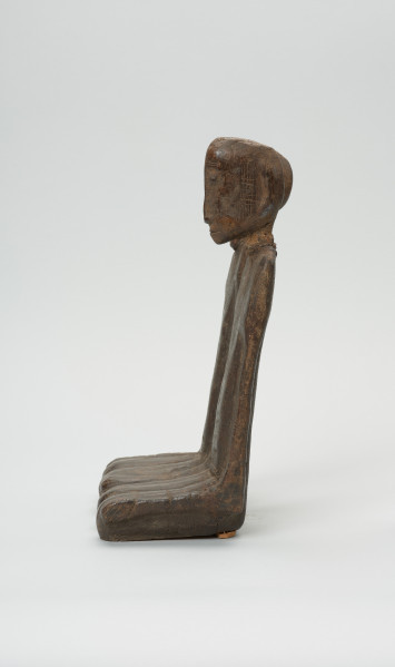 drewniana figura - Ujęcie z prawego boku. Para przodków siedzących obok siebie, ręce przylegające wzdłuż tułowia.