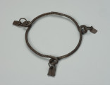 bransoleta, biżuteria - Ujęcie z dołu. Zamknięta, żelazna, okrągła bransoleta z trzema pętelkami do których przymocowane są żelazne wisiorki w kształcie trapezu.
