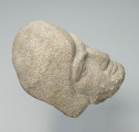 głowa - Ujęcie w poziomie; Głowa mężczyzny w kapuzie z szarożołtego kamienia. Twarz pociągła okolona niewielkim zarostem, między brwiami fałda, rysy wydatne.