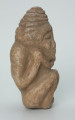 rzeźba; przedmiot obrzędowy; Figura kultu zmarłych - Ujęcie prawy bok. Rzeźbiona w szarobeżowym steatycie postać ludzka ze spiralną linią na czubku dużej głowy, siedząca z przykurczonymi nogami i trzymająca w dłoniach bliżej nieokreślone przedmioty, kształtem przypominające motyki.
