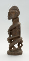 drewniana, rzeźbiona figura - Ujęcie z lewego boku. Drewniana, rzeźbiona postać kobiety, trzymającej w ramionach małe dziecko.