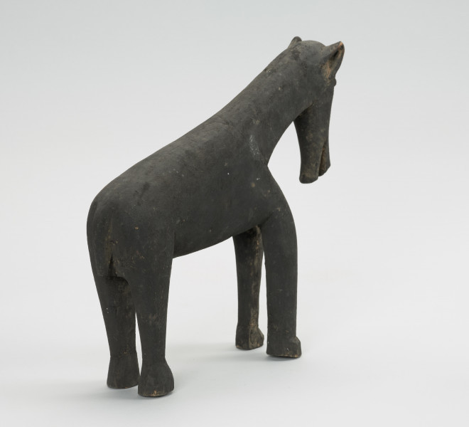 figura zoomorficzna: koń - Ujęcie z tyłu skosem w prawą stronę. Drewniana, rzeźbiona figura konia.