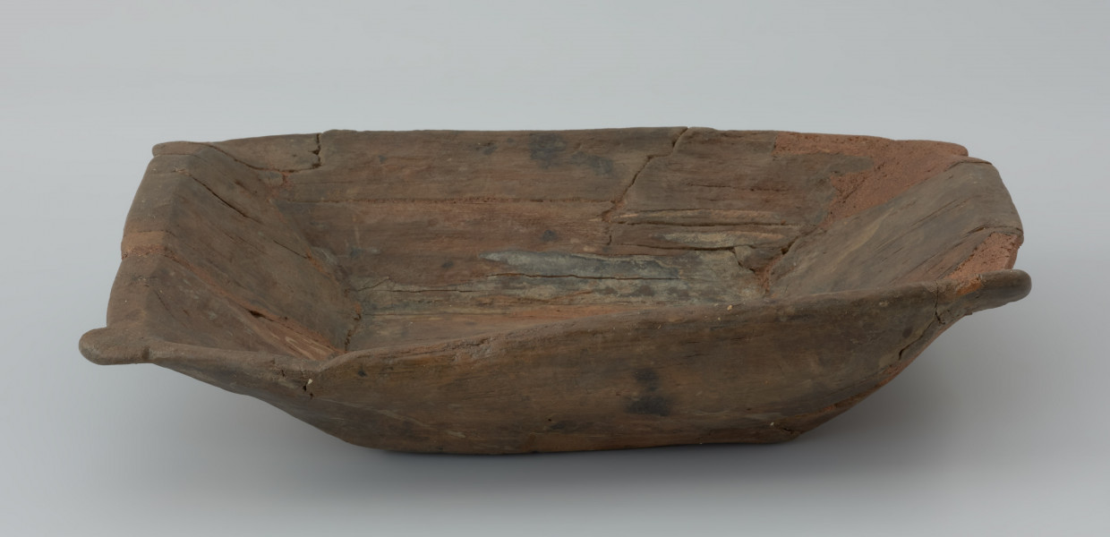 Niecka drewniana; dzieża - Ujęcie lewego dłuższego boku dzieży.  Płytka niecka wydrążona w przepołowionym pniu drzewa liściastego, zaopatrzona w uchwyty ułatwiające przenoszenie
