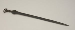 broń - Ujęcie przodu miecza. Brązowy miecz posiada czworokątną rękojeść z nerkowatym pałąkiem oraz dzwonowaty jelec.