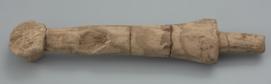 Mieczyk drewniany - Ujęcie z góry tyłu skosem w górę.  Drewniany mieczyk-zabawka z okrągłą głowicą kończącą lekko zwężoną rękojeść, bez jelca, z głownią płaską, ułamaną .