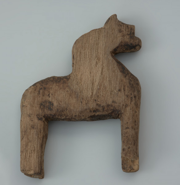 przedmiot kultowy, figurka - Ujęcie lewego boku z góry. Drewniana figurka antropomorficzna jednotwarzowa, ze schematycznie zaznaczonymi kończynami, tzw. idol, została wyciosana z jednego kawałka drewna.