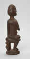 rzeźba - Ujęcie prawego boku. Drewniana, rzeźbiona postać z dzieckiem w pozycji siedzącej. Figura pokryta drobnym, dekoracyjnym rytem. Dziecko leżące w pozycji embrionalnej. Ramiona kobiety zaokrąglone.