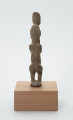 rzeźba - Ujęcie z tyłu. Figura - postać mężczyzny w pozycji stojącej z ugiętym kolanami. Ręce i dłonie nieproporcjonalnie długie/duże w stosunku do całej postaci. Ręce zakrywają twarz, dłonie sterczą ponad głową. Rzeźba związana z kultem przodków.