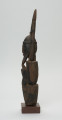 rzeźba - Ujęcie lewego boku. Figurka przedstawia Hogona – kapłana kultu Lebe. Widoczna broda, wyprostowane ręce uniesione do góry.