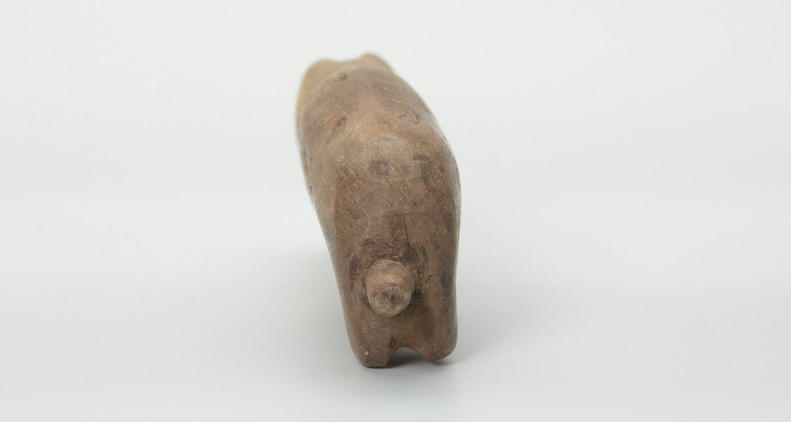 Drewniana figura zwierzęcia z krótkim ogonem - Ujęcie z tyłu. Drewniana figurka nieokreślonego zwierzęcia z długą szyją, podłużną głową i krótkim ogonem.