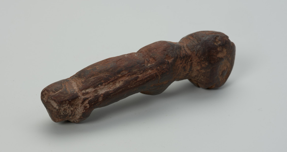 Drewniana figurka zwierzęcia - Ujęcie z prawego boku.  Drewniana figurka zwierzęcia. Forma bardzo uproszczona, z bryły symbolicznie wyodrębnione: głowa, tylne i przednie kończyny oraz ogon.