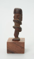 Drewniana figurka postaci ludzkiej z dużą głową i krótkimi nogami. - Ujęcie z prawej strony; drewniana figurka postaci ludzkiej. Głowa zajmuje większość powierzchni rzeźby. Nos wąski, długi, w kształcie strzałki. Brak tułowia. Krótkie nogi.