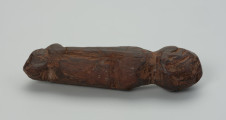 Drewniana figurka zwierzęcia - Ujęcie z boku, mocno zwrócone w lewą stronę. Drewniana figurka zwierzęcia. Forma bardzo uproszczona, z bryły symbolicznie wyodrębnione: głowa, tylne i przednie kończyny oraz ogon.