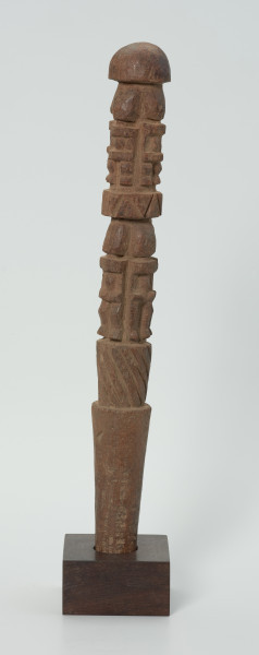 drewniana, rzeźbiona pałka - Ujęcie z lewego boku. Okrągła, drewniana pałka z płytko rzeźbionymi dwoma rzędami postaci ludzkich. W każdym rzędzie zaznaczonych zostało czterech przodków, bez wyraźnie zaznaczonych cech płciowych.