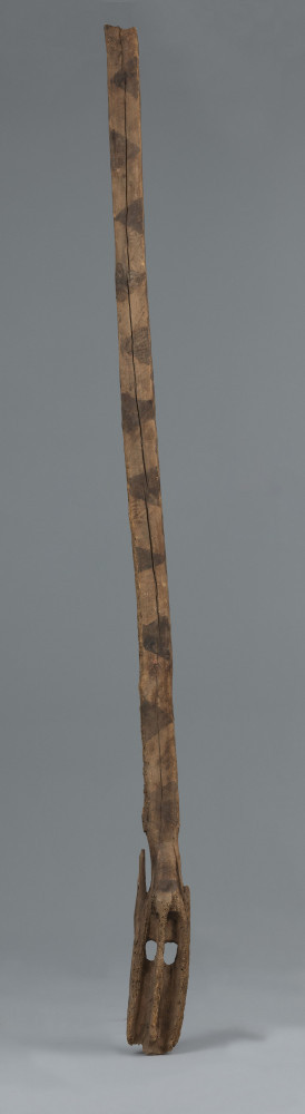 maska imina - Ujęcie z przodu. Drewniana, długa, pionowa maska, pomalowana w czarne trójkąty.