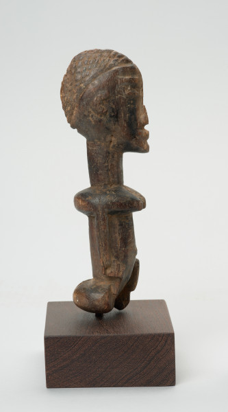 rzeźba - Ujęcie prawego boku. Figura przedstawiająca postać kobiety. Duża głowa, z zaznaczoną fryzurą, ręce prostymi cięciami wydobyte z tułowia. Figura kanoniczna. Brak nóg. Związana z kultem przodków.