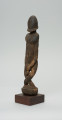 rzeźba - Ujęcie z przodu z lewej strony. Figura przedstawiająca postać przodka -  mężczyznę ze skrzyżowanymi nogami. Figura antropomorficzna, oddająca cechy dogońskiego kanonu przedstawiania ludzi.