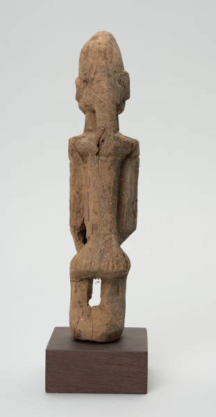rzeźba - Ujęcie z tyłu; Figura - postać mężczyzny w pozycji stojącej. O płci świadczy bródka. Części ciała płaskorzeźbione z bryły. Forma uproszczona, zgeometryzowana. Związana z kultem przodków, przeznaczona na ołtarz przodków.