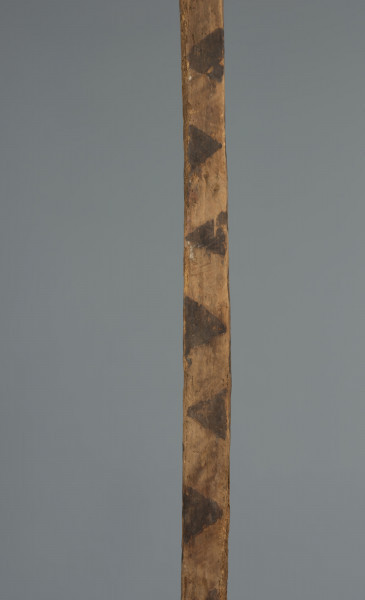 maska imina - Ujęcie detalu górnej części. Drewniana, długa, pionowa maska, pomalowana w czarne trójkąty.