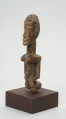 rzeźba - Ujęcie z przodu z lewej strony. Figura przedstawiająca postać kobiety. Duża głowa, z zaznaczoną fryzurą, ręce prostymi cięciami wydobyte z tułowia. Figura kanoniczna. Brak nóg. Związana z kultem przodków.
