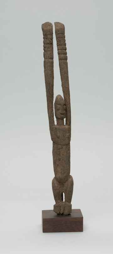 rzeźba - Ujęcie z przodu. Figura antropomorficzna przedstawiająca postać z rękoma wyciągniętymi do góry. Ręce nieproporcjonalnie długie.