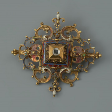rozeta z kołpaka księcia Filipa II (1573-1618) - Ujęcie z przodu. Klejnot zbudowany z dwóch skręconych śrubą części: ażurowego stelaża o romboidalnym kształcie i osadzonej na nim wysokiej, kasetowej oprawy, ujmującej diament o szlifie tablicowym. Stelaż i ścianki kasztu pokryte są barwną emalią, korpusową, a także żłobkową, z wzorami rezerwowanymi w złocie. Rozety mają na spodniej stronie, w narożach, haczyki umożliwiające spinanie ich w łańcuch, a także uszka pozwalające na ich mocowanie do stroju.