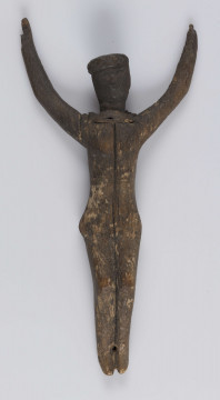 E/5175/ML - Rzeźba drewniana przedstawiająca Chrystusa Ukrzyżowanego. Głowa lekko pochylona. Twarz potraktowana schematycznie. Korona cierniowa w postaci opaski zdobionej rytem ukośnych rombów. Ręce łukowato wygięte ku górze, słabo zaznaczona klatka piersiowa, biodra silnie wystające, nogi lekko zgięte w kolanach, stopy słabo zaznaczone. Drewno prawdopodobnie lipowe. Figurka pęknięta wzdłuż. Brak krzyża.