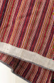 Spódnica zszywana 4 pasów (szer. 52 cm) tkaniny lniano-wełnianej, tkanej na warsztacie splotem prostym w pasy. Marszczona i wszyta w pasek z granatowego płótna. Dół wzmocniony pasem szarego płótna. Na czerwonym tle pionowe pasy w kolorach: zielonym i białym. Wiązana na troczki ze sznurka.