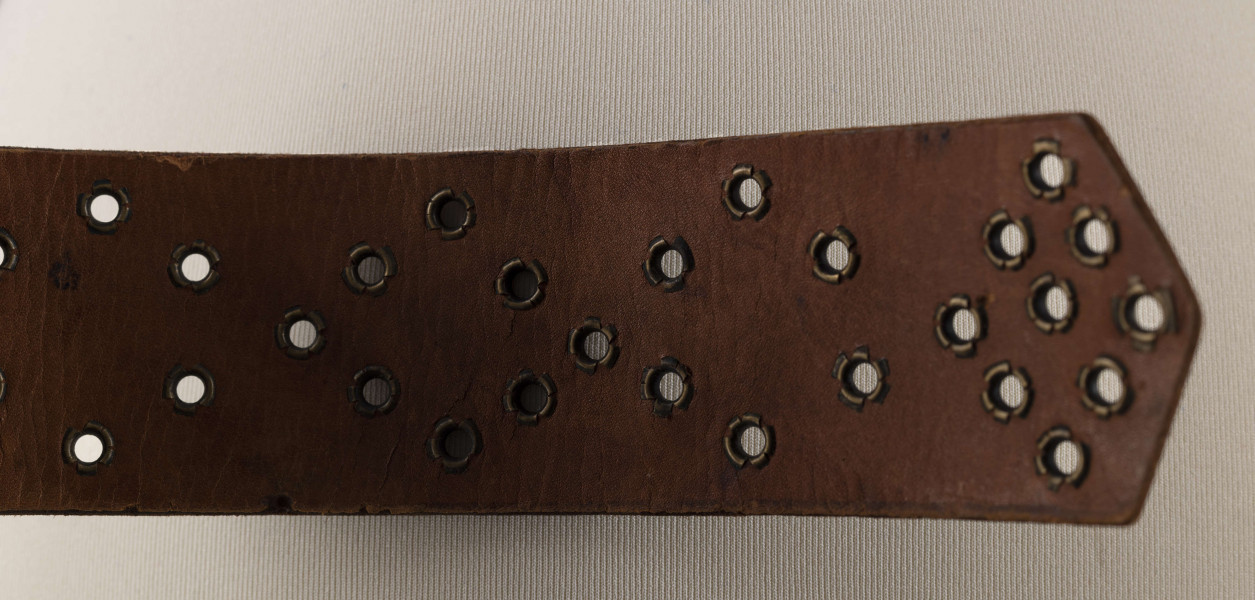 E/706/ML - Pas męski wykonany ze skóry koloru czarnego, z mosiężną klamrą. Ozdobiony ornamentem w postaci punktów wytłaczanych stemplem. Dziurki obłożone mosiężnymi kółeczkami.